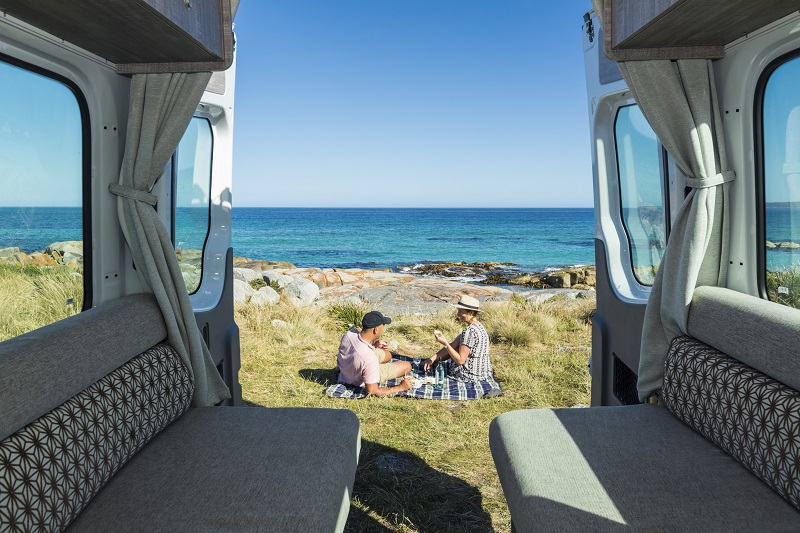 View from inside RV of a couple sitting near ocean